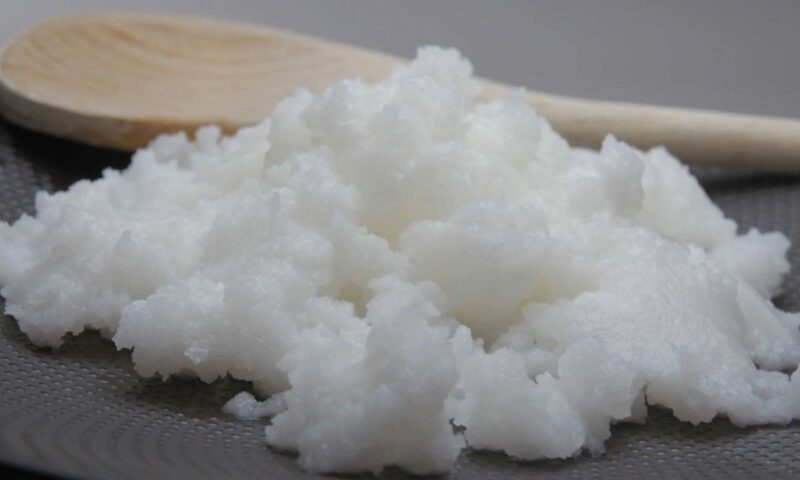 prikaz kokosovog ulja sa drvenom varjačom pored